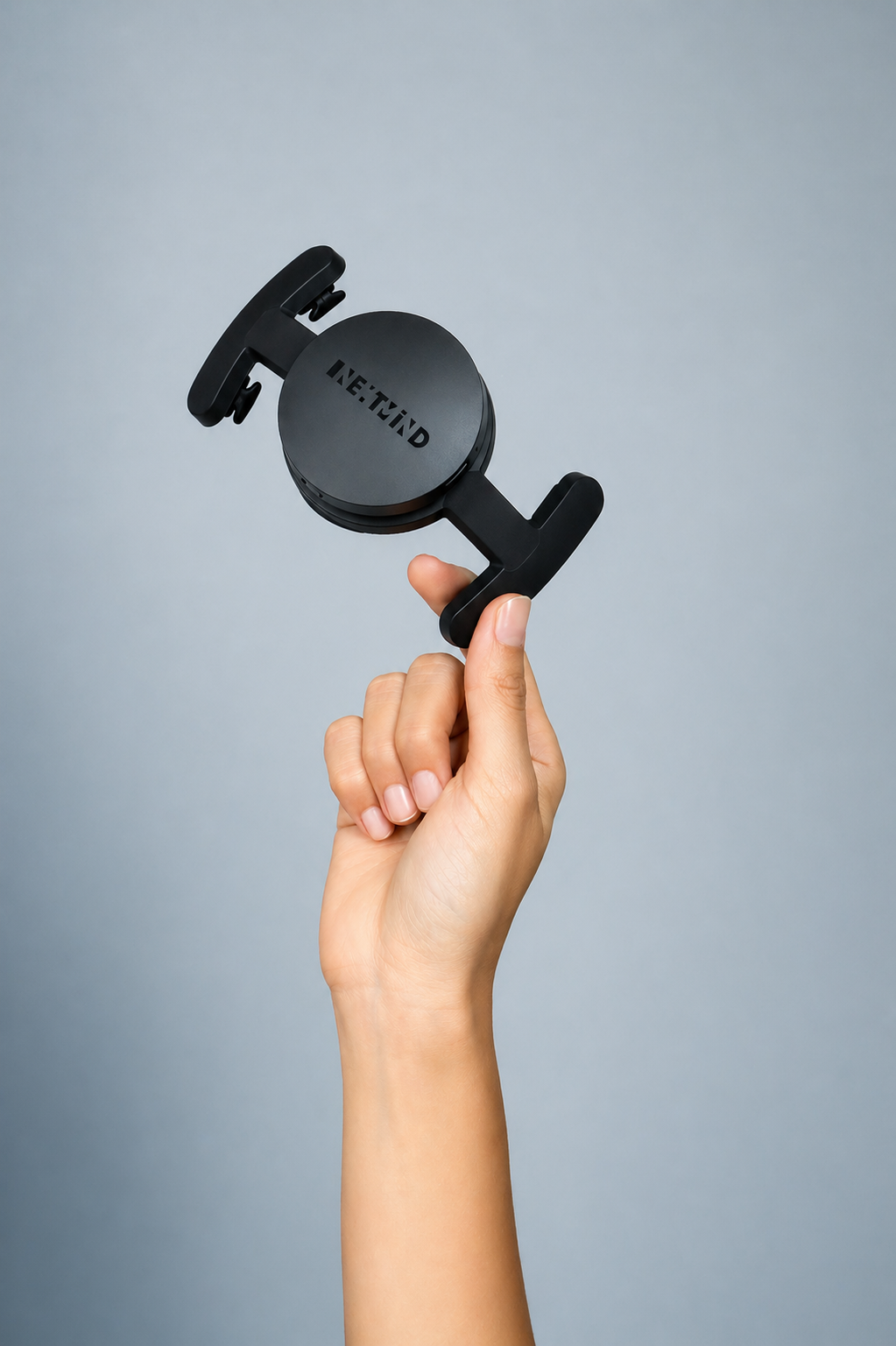 NextMind device balanced on a fingertip, product photography